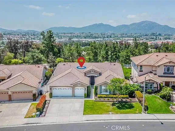 Aerial view of California real estate houses with mountains and trees, one marked by location pin