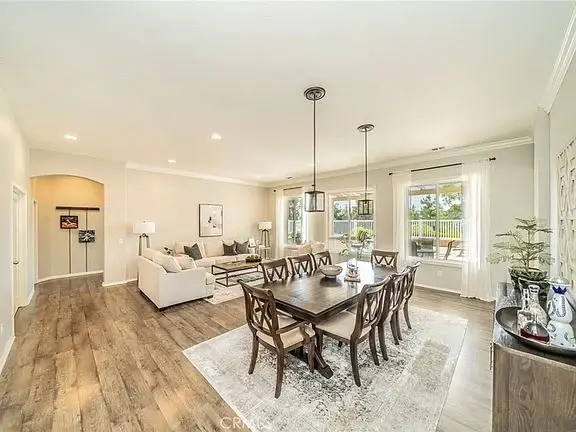 Dining area with large table and chairs, and living room with couch in background