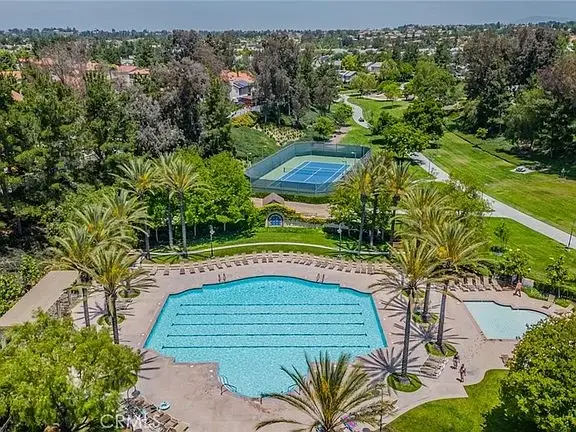 Aerial view of California real estate house with swimming pool, palm trees, tennis courts, and park area