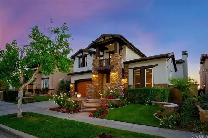 Two story house California real estate with stone accents, plants, and colorful flowers.
