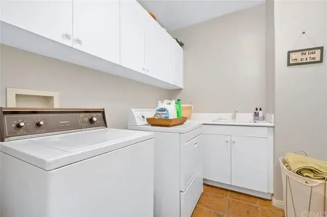 Laundry room with washing machine, dryer, and storage cabinets.