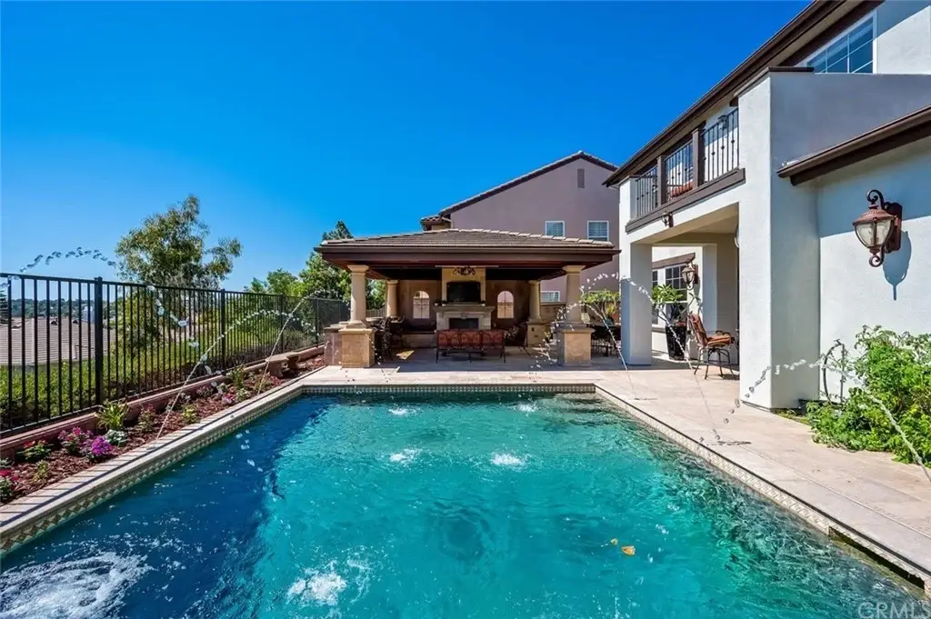 Backyard of house California real estate with pool, fountain, garden, and covered patio.