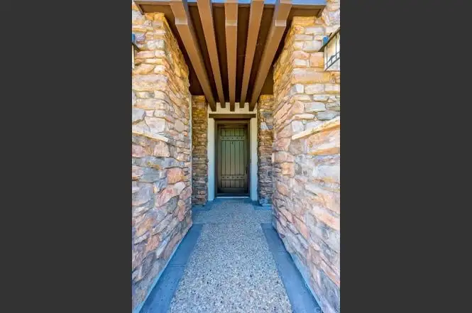 Stone walkway to house California real estate wooden door with stone walls and roof.
