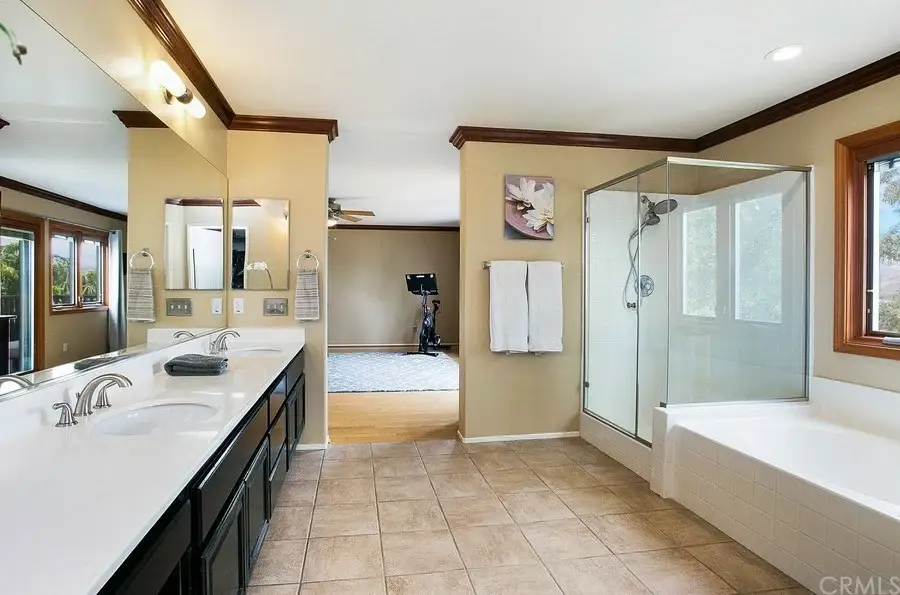 bathroom with double sink vanities, glass shower, separate bathtub, and large windows with natural light.