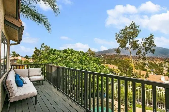 Balcony with sofa overlooking trees and hills.