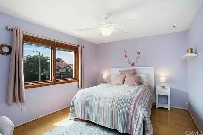 Bedroom with light purple walls, striped bedding, and two bedside lamps on white nightstand
