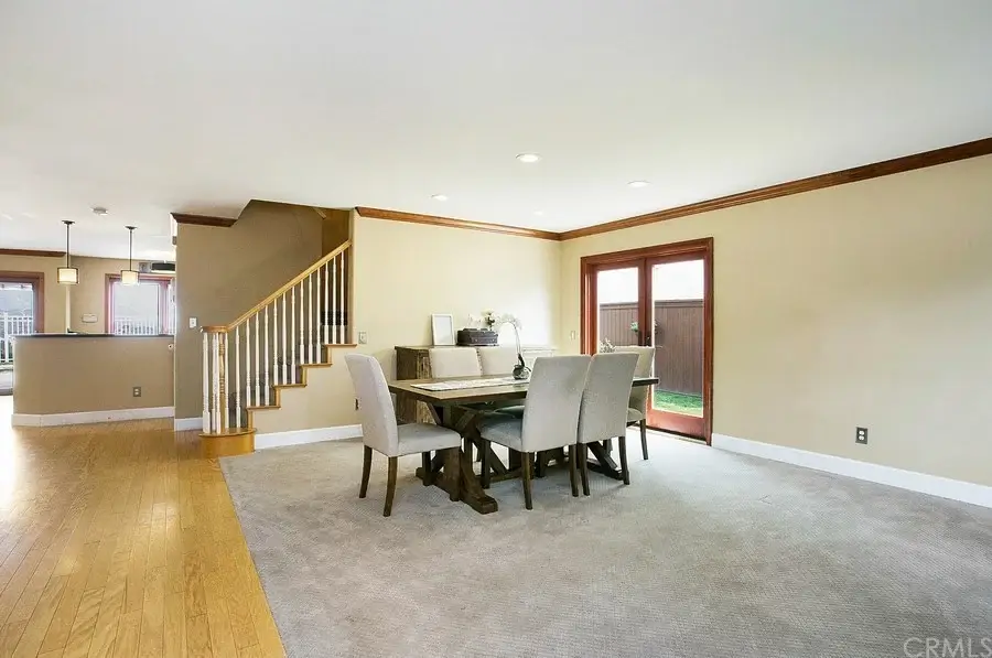 dining area with wooden table and chairs, large windows, sliding door outside, carpet and staircase.