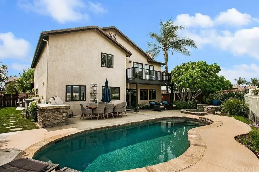 Backyard of house California real estate with pool, patio furniture, and green plants.