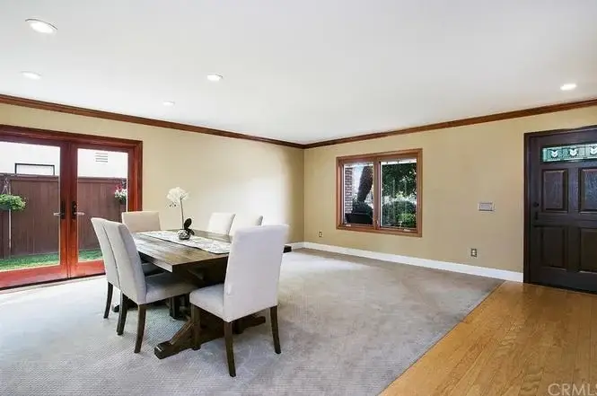 dining area with wooden table, upholstered chairs, large windows, French doors to garden, and carpet and hardwood floor.