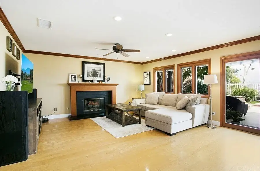 Living room with beige sectional sofa, dark wood coffee table, fireplace, and windows with outdoor view.