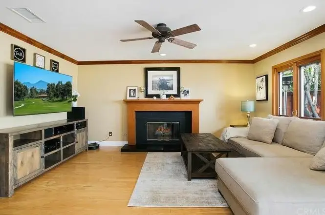 Living room with large sectional sofa, wooden coffee table, fireplace, TV, and natural light from windows.