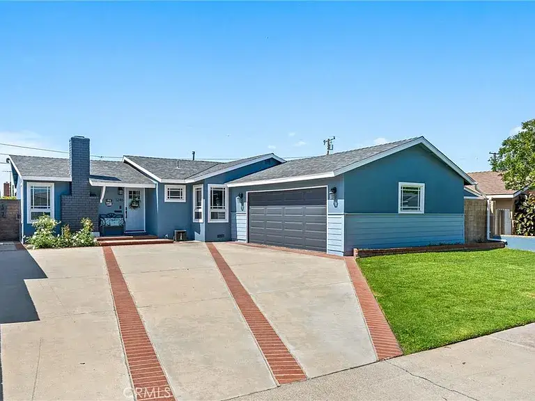 Single story house California real estate with blue exterior, green lawn, driveway, and two car garage.
