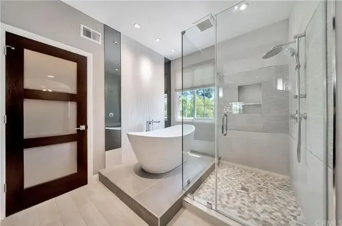 Bathroom with freestanding tub, glass shower, large window, tile floor, and neutral walls.