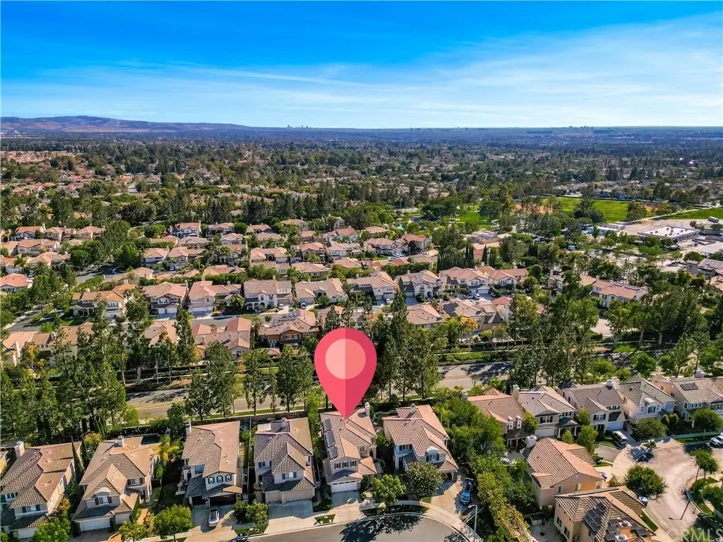 Aerial view of houses California real estate with greenery and location pin.