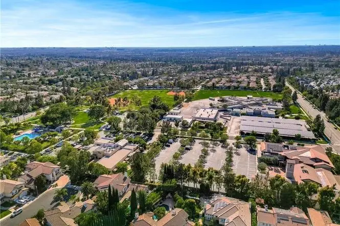 Aerial view of houses California real estate with parks, parking lot, and hills.