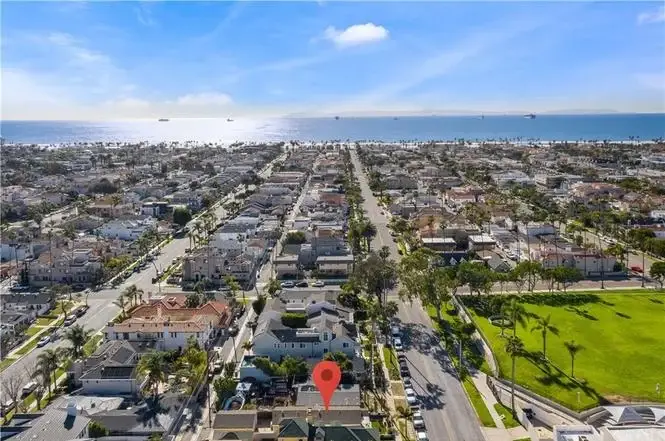 Aerial view of California real estate houses, roads, and ocean with red location marker