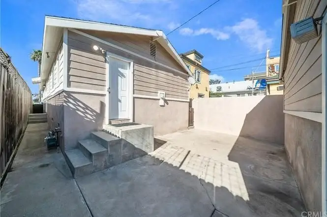 California real estate house with stairs, white door, and concrete area surrounded by walls