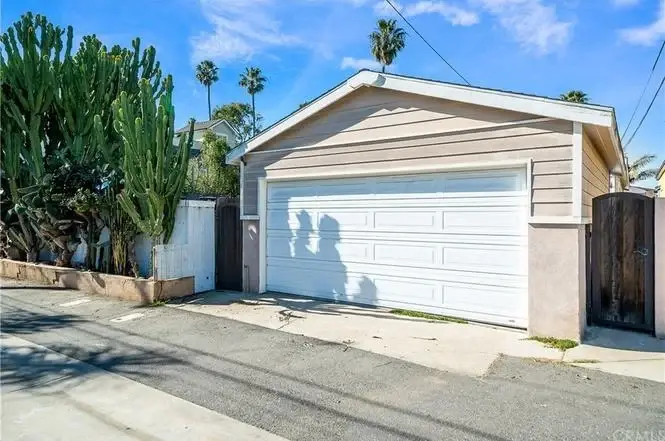 California real estate garage with white door, palm trees, and tall cactus