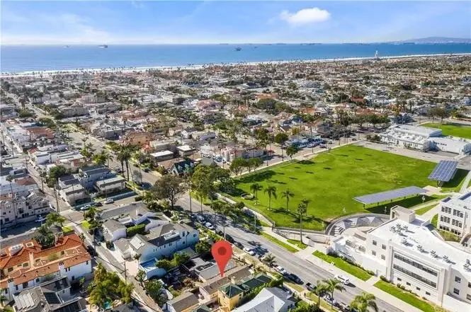 Aerial view of California coastal homes, parks, and ocean with a location marker on a property.