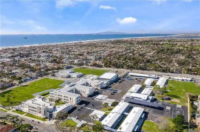 Aerial view of California coastal real estate with homes, parks, ocean, and a location marker on a property.
