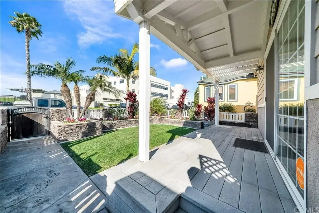 Patio with landscaped garden, palm trees, shrubs, and houses in background