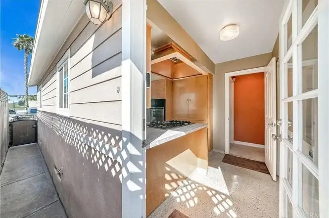 Corridor with light walls leading to kitchen with gas stove and door at end