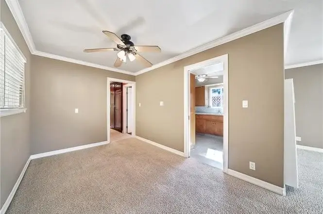 Room with light walls, carpet, ceiling fan, doorways, and windows