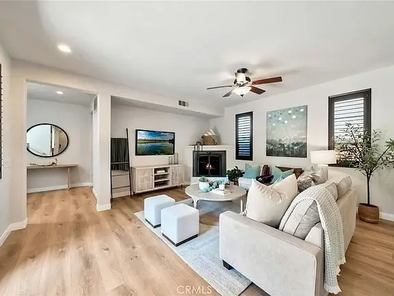 Living room with ceiling fan, round coffee table, comfortable seating, TV, fireplace, and windows