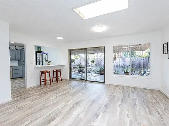 Room with wood floor, sliding glass doors to patio, and small bar with two stools.