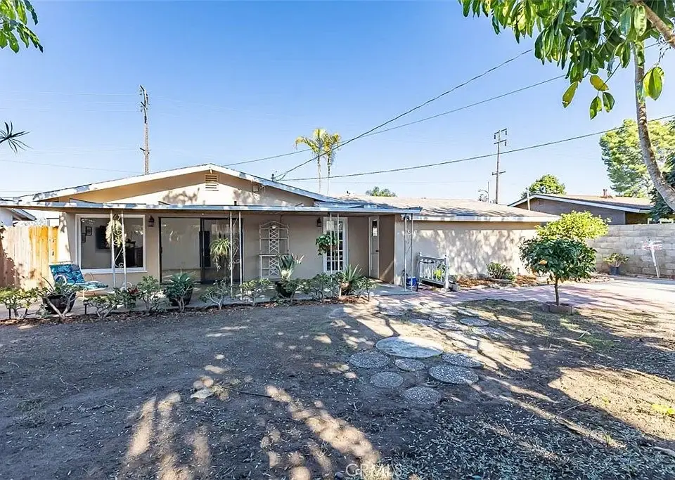 Single-story California real estate house with a front lawn, garden, and surrounding trees.