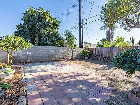 Spacious outdoor area with a paved patio, small trees