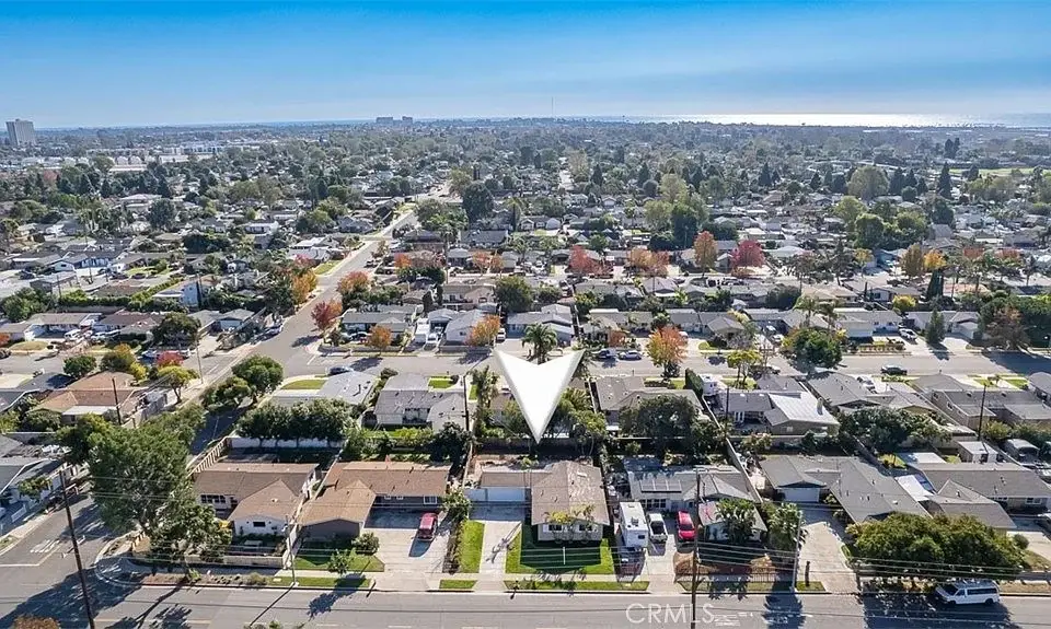 Aerial view of a suburban area with streets, many California real estate houses, and the ocean in the background.