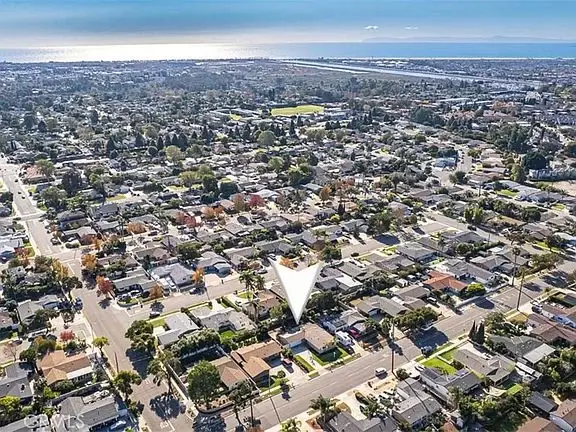 Aerial view of a suburban area with streets, California real estate houses, and a distant coastline.