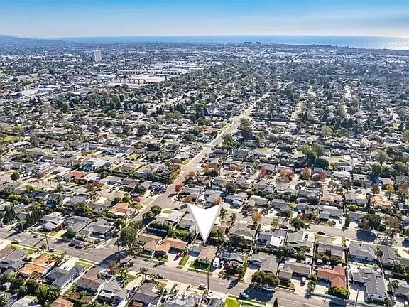 Aerial view of a suburban area with streets, California real estate houses, and a distant coastline.