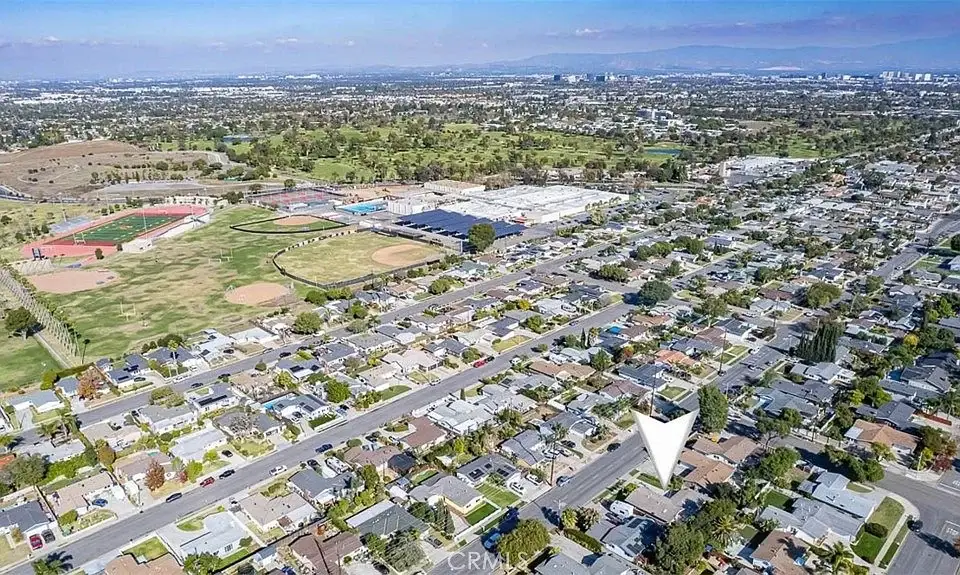 Aerial view of a suburban neighborhood with California real estate houses, streets, and nearby sports fields.