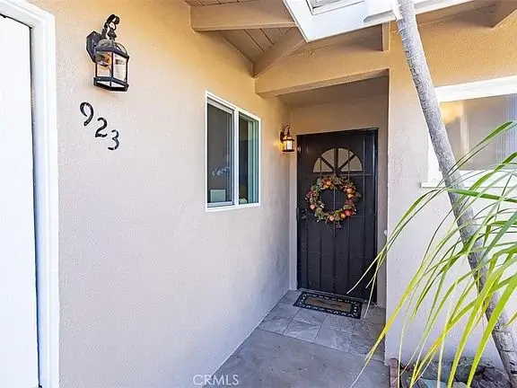 Front door of house California real estate with black door, wreath, number 923, lantern, and plant.