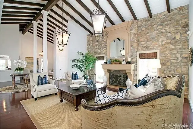 Living room with large sofa, wooden coffee table, framed photos, high beam ceiling