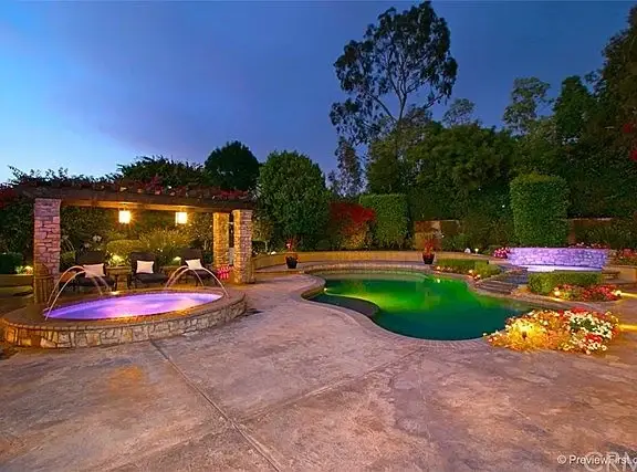 Backyard of house California real estate with pool, hot tub, plants, and flowers.