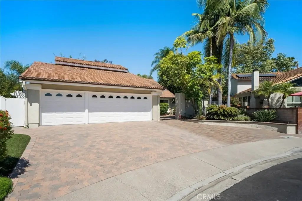 Large luxury house California real estate garage with paved driveway, palm trees, and landscaping.
